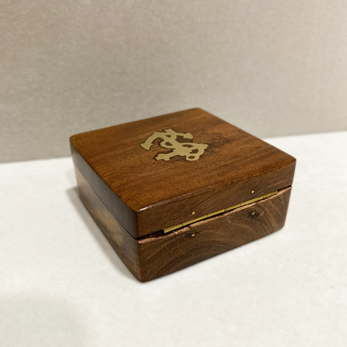 Caixa de madeira fechada com incrustação da âncora em latão para bússola de navegação vista de dobradiça