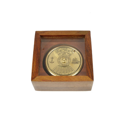 Calendário perpétuo circular em latão dourado polido da Loja do Museu de Marinha, mostrando o disco mecânico de 100 anos com gravações de uma caravela e de uma âncora.