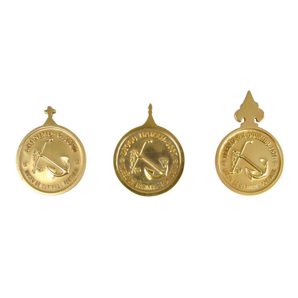 Verso dourado brilhante das três medalhas da Rosa dos Ventos, destacando os passadores superiores de fixação e o acabamento liso de coleção.