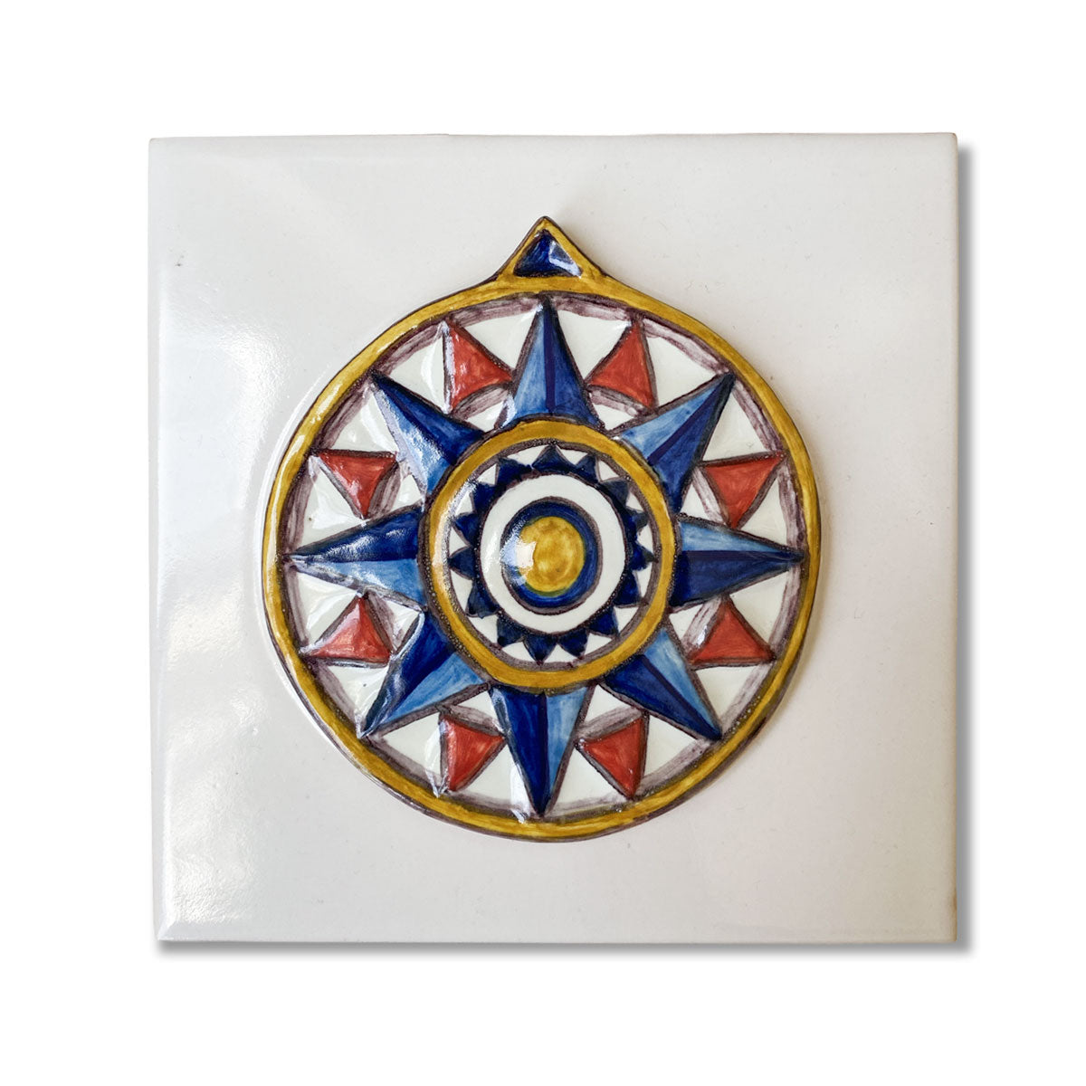 Azulejo quadrado em cerâmica vidrada branca exibindo uma rosa dos ventos geométrica em relevo pintada à mão em tons de azul, vermelho e amarelo, com acabamento tridimensional.