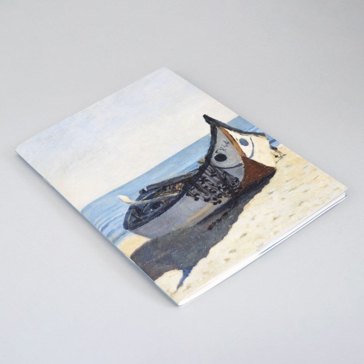 Coleção exclusiva de cadernos de notas João Vaz do Museu de Marinha sobre mesa de madeira, mostrando capas ilustradas com pinturas de barcos tradicionais e pescadores portugueses.