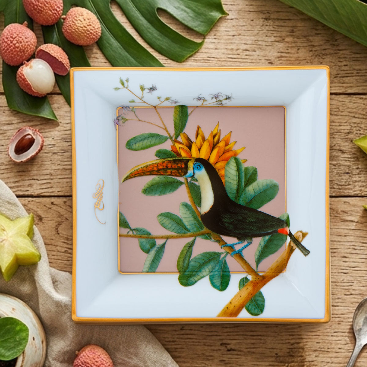 Bandeja quadrada em porcelana Vista Alegre coleção Amazónia com ilustração de tucano e detalhes dourados.