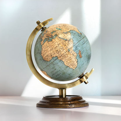 Globo terrestre clássico compacto de 18cm de altura sobre base de madeira e suporte de latão dourado, com cartografia detalhada em tons ocre e azul suave.
