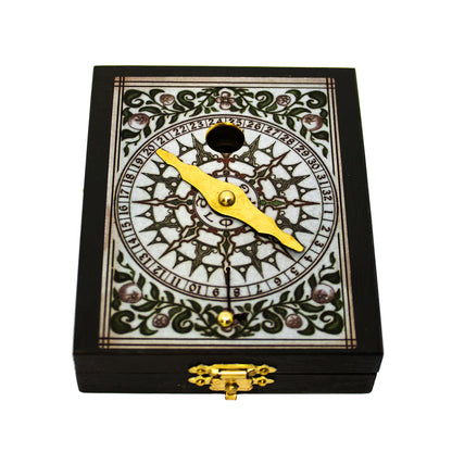 Bússola Kepler fechada na sua caixa de madeira retangular escura, destacando o fecho metálico dourado e o topo decorado com mostrador ornamental numérico e ponteiro.