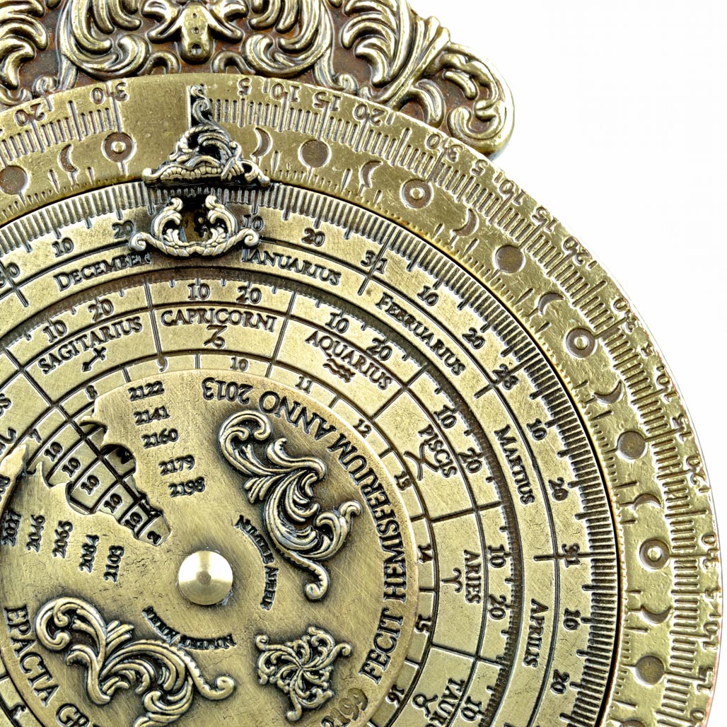 Pormenor de réplica de instrumento náutico Calendário Lunar Perpétuo em latão gravado sobre base de madeira.