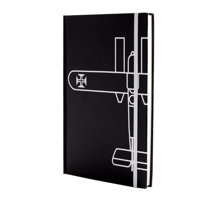 Caderno de capa dura preta tamanho A5 com desenho minimalista em linhas brancas do Hidroavião Santa Cruz de Gago Coutinho e elástico de fecho vertical branco.