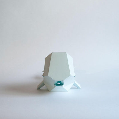Candeeiro decorativo de papel em formato de baleia cachalote com design geométrico moderno aceso, emitindo uma luz suave sobre uma superfície plana.
