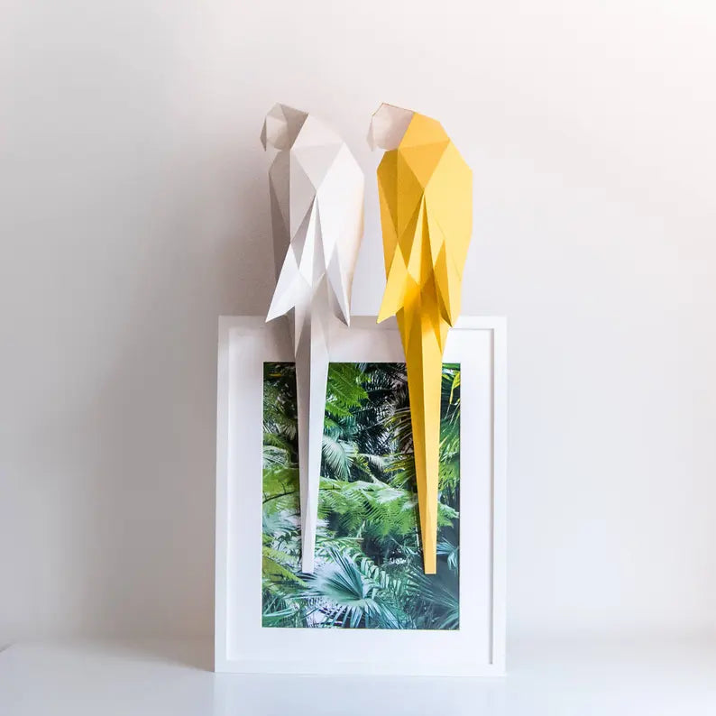 Candeeiro decorativo geométrico de papel em formato de papagaio tropical aceso sobre uma mesa, emitindo uma luz quente e realçando o design papercraft.
