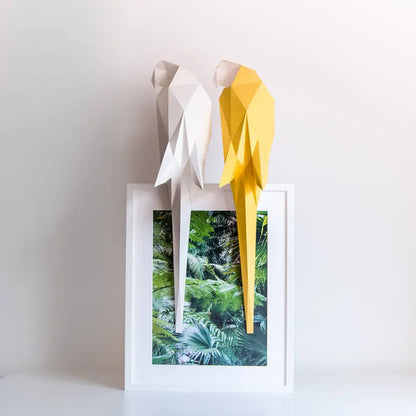 Candeeiro decorativo geométrico de papel em formato de papagaio tropical aceso sobre uma mesa, emitindo uma luz quente e realçando o design papercraft.